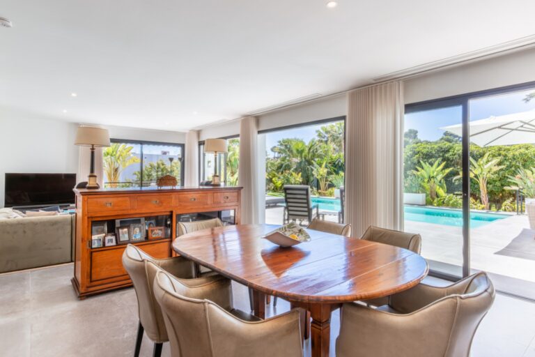 Dining area inside a modern villa in Solpark, Moraira with wooden dining table, pool views, large sliding doors and bright open-plan layout