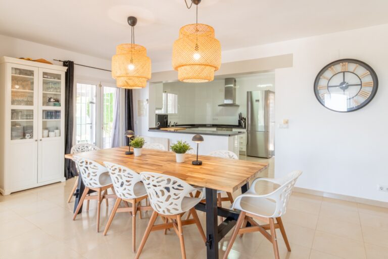 Dining area inside a renovated Mediterranean villa in Moraira with wooden dining table, open kitchen, pendant lighting and bright modern interior