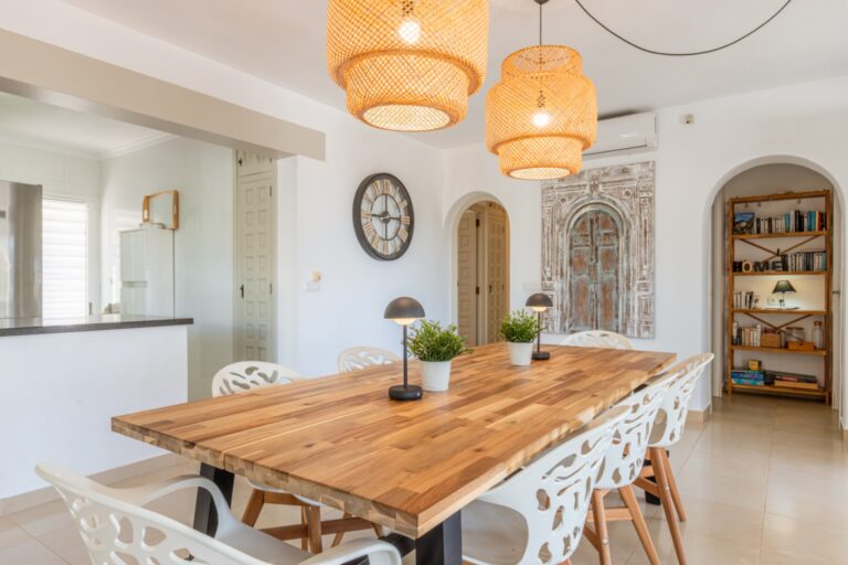 Dining area inside a renovated Mediterranean villa in Moraira with wooden dining table, pendant lighting, kitchen access and bright interior