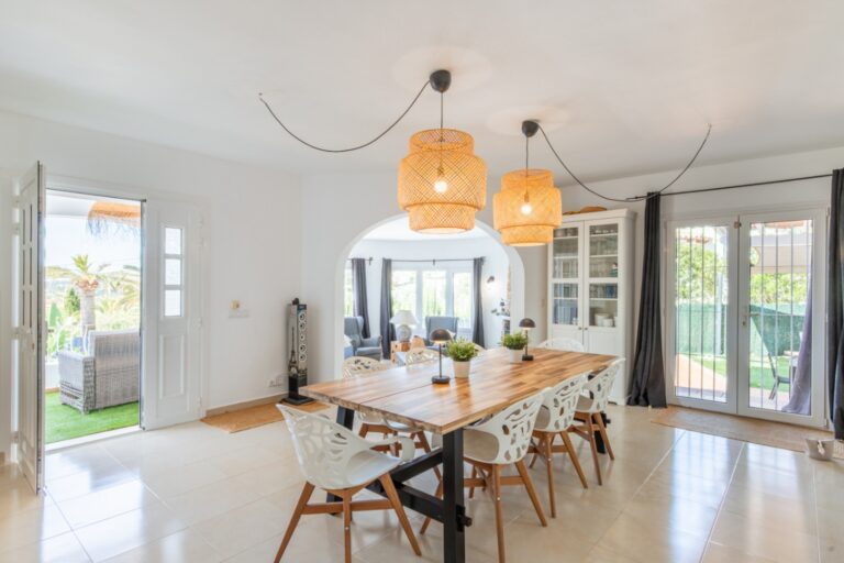 Dining area inside a renovated Mediterranean villa in Moraira with wooden dining table, pendant lighting, terrace access and bright open-plan layout