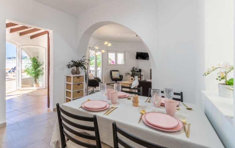 Dining area inside a renovated villa near Cala Baladrar in Benissa Costa with set dining table, arched opening, terrace access and bright Mediterranean interior