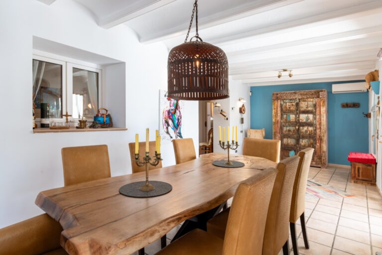 Dining room inside a renovated finca near Teulada and Moraira with wooden dining table, pendant lighting, blue feature wall and traditional interior details