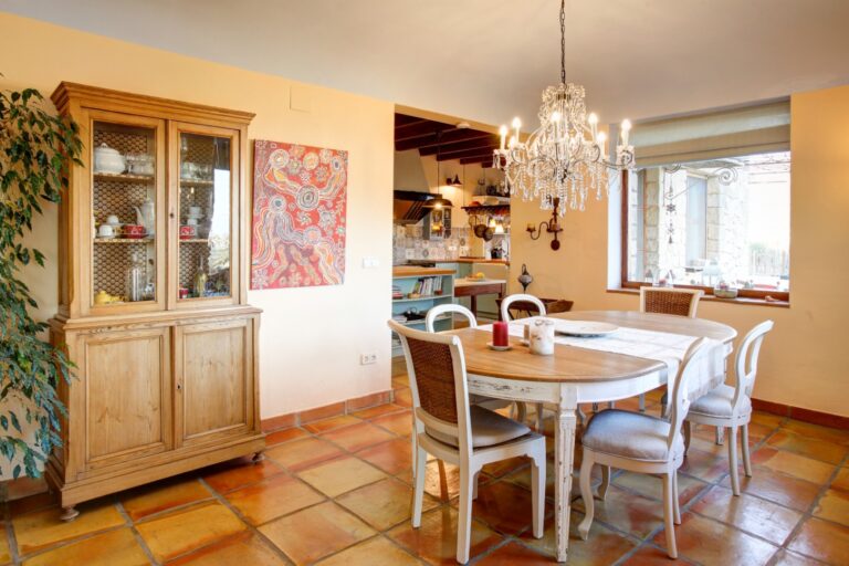 Dining room inside a rustic Mediterranean estate near Moraira with chandelier, terracotta flooring, traditional dining furniture and kitchen access