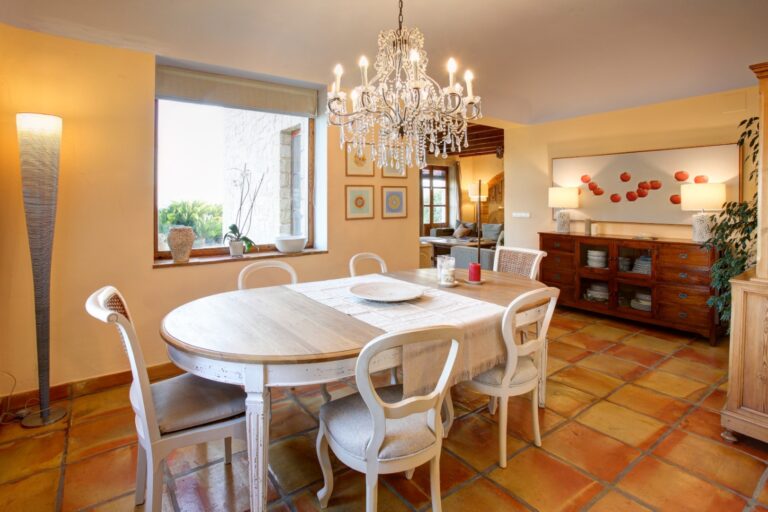 Dining room inside a rustic Mediterranean estate near Moraira with chandelier, terracotta flooring, traditional dining table and warm Mediterranean interior