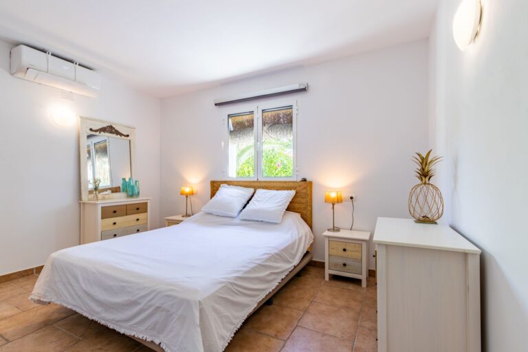 Double bedroom inside a Mediterranean villa near Cala Baladrar in Benissa Costa with air conditioning, bedside tables, natural light and neutral finish