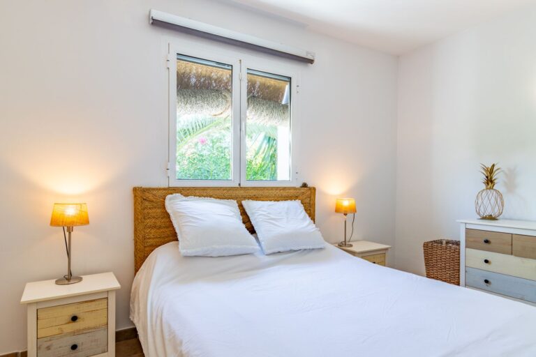Double bedroom inside a Mediterranean villa near Cala Baladrar in Benissa Costa with white walls, wooden bed, bedside tables and natural light