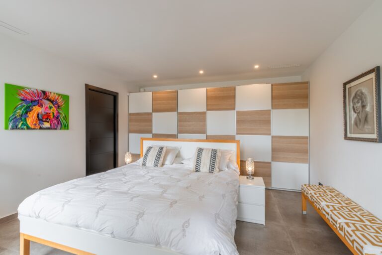 Double bedroom inside a modern villa in Solpark, Moraira with feature wall, fitted wardrobes, double bed and contemporary neutral design