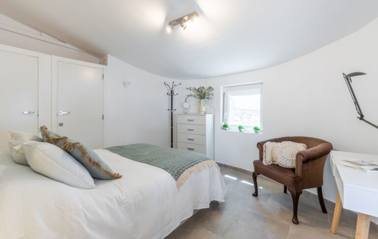 Double bedroom inside a renovated Mediterranean villa near Cala Baladrar in Benissa Costa with fitted wardrobes, desk area, armchair and bright neutral interior