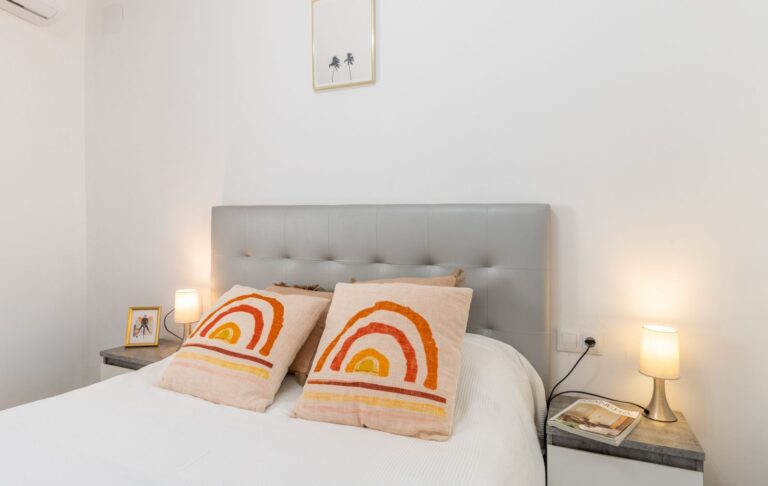Double bedroom inside a renovated villa near Cala Baladrar in Benissa Costa with grey headboard, bedside lamps and neutral modern styling