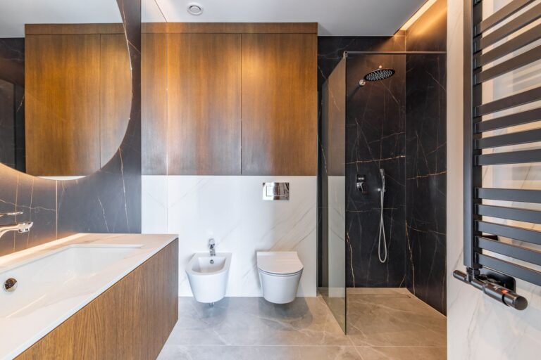 En-suite bathroom inside a luxury smart home villa near Moraira with walk-in shower, wooden vanity, black feature wall, toilet and premium finishes