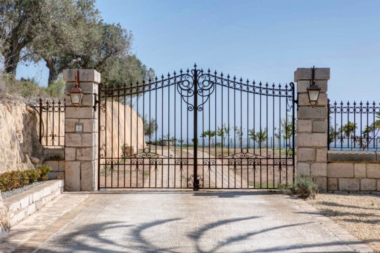 Entrance gate at a rustic Mediterranean estate near Moraira with wrought iron gates, stone pillars, private driveway and countryside surroundings