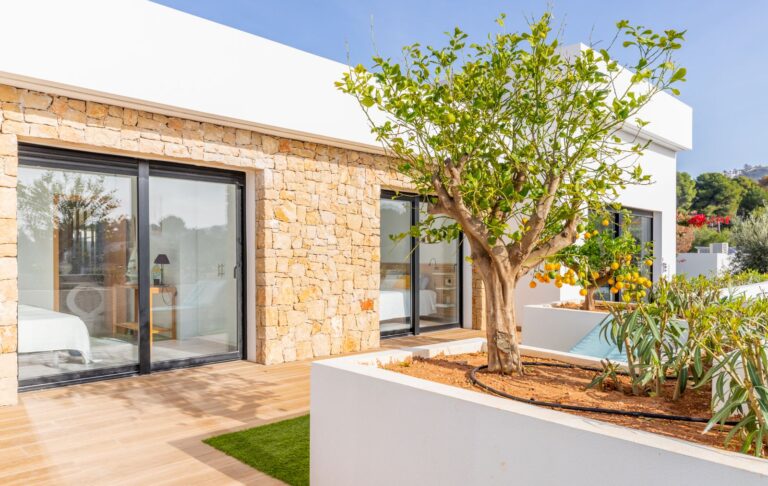 Exterior terrace at a modern villa in Pla del Mar, Moraira with natural stone detail, large sliding doors, garden planting and contemporary architecture