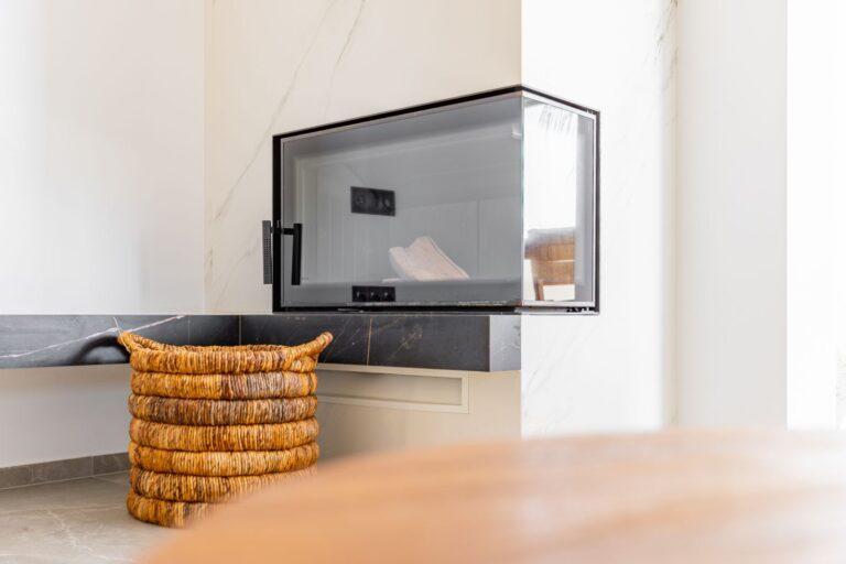 Fireplace detail inside a luxury smart home villa near Moraira with modern glass fireplace, natural stone finish, dining area and bright interior