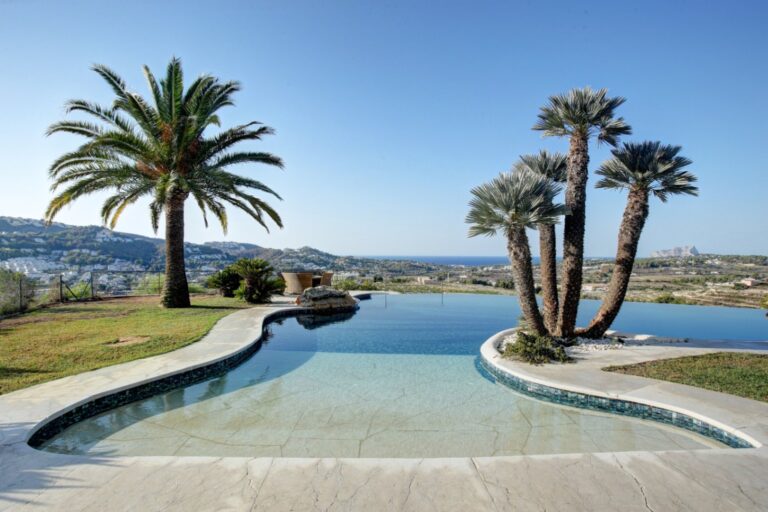 Freeform swimming pool at a rustic Mediterranean estate near Moraira with palm trees, open countryside views and private outdoor surroundings