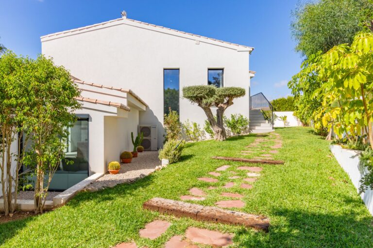 Garden path beside a luxury smart home villa near Moraira with white exterior, lawn, Mediterranean planting and private outdoor space
