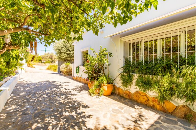 Garden walkway at a Mediterranean villa near Cala Baladrar in Benissa Costa with mature planting, white exterior walls and private outdoor setting