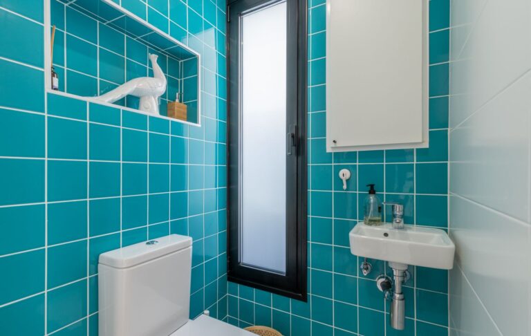 Guest toilet inside a modern villa in Pla del Mar, Moraira with turquoise tiled walls, compact sink, toilet and contemporary finish