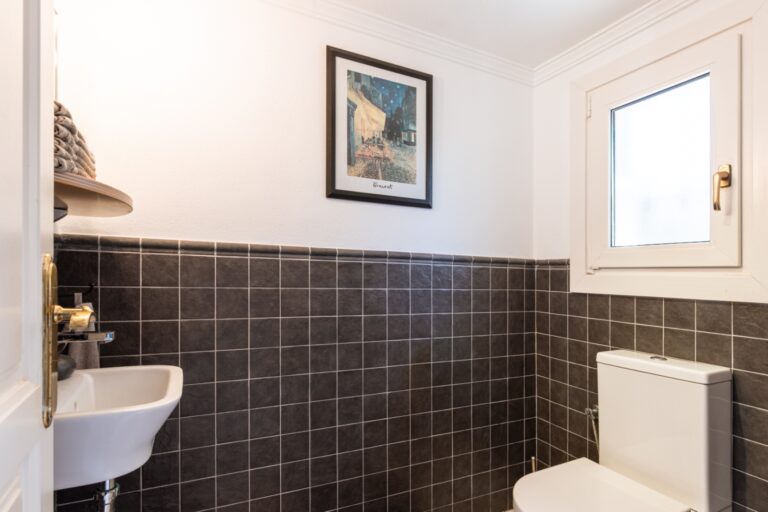 Guest toilet inside a renovated finca near Teulada and Moraira with compact sink, tiled walls, window and bright traditional finish