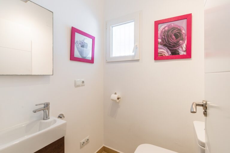 Guest toilet inside a renovated Mediterranean villa in Moraira with compact sink, toilet, bright window and simple modern finish
