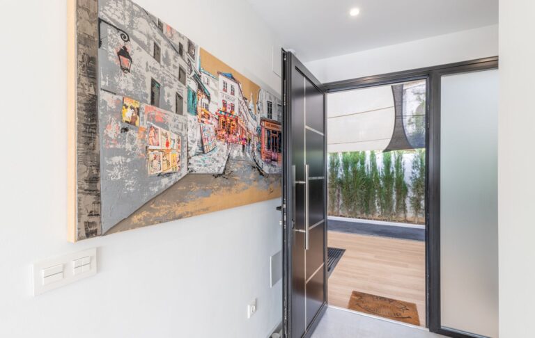 Hallway inside a modern villa in Pla del Mar, Moraira with contemporary wall art, glass door, terrace access and bright white interior