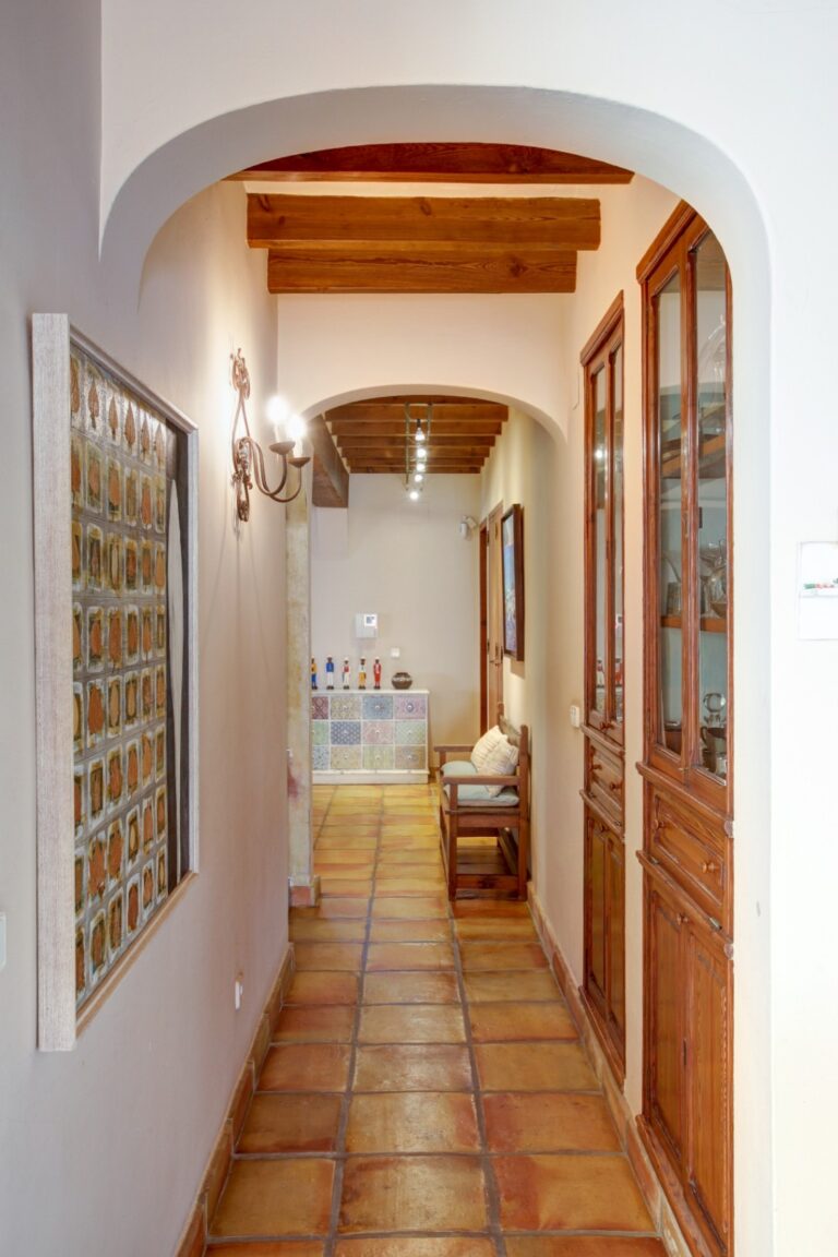 Hallway inside a rustic Mediterranean estate near Moraira with arched doorway, terracotta flooring, wooden doors and traditional interior details