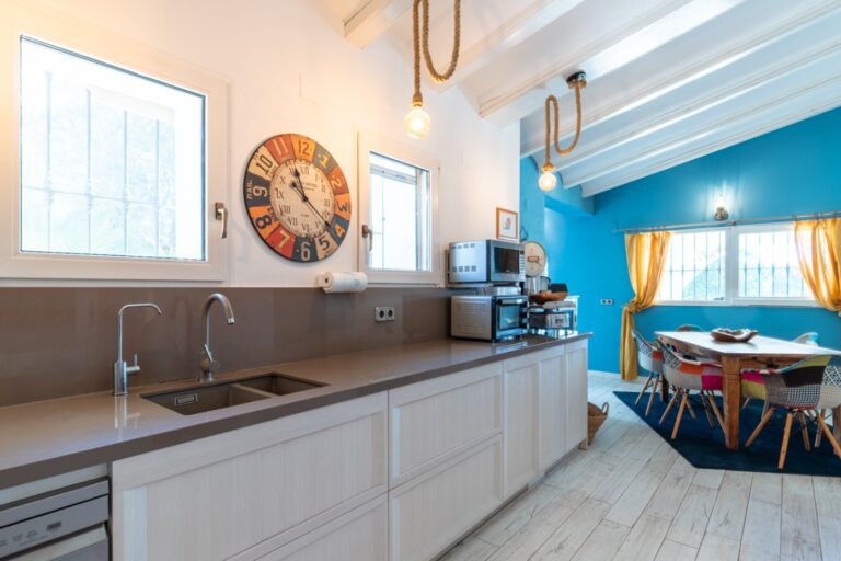 Kitchen and dining area inside a renovated finca near Teulada and Moraira with fitted cabinetry, blue feature wall, dining table and bright windows