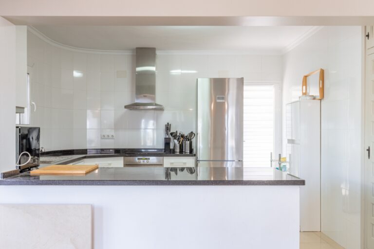 Kitchen inside a renovated Mediterranean villa in Moraira with breakfast bar, white cabinetry, modern appliances and bright windows