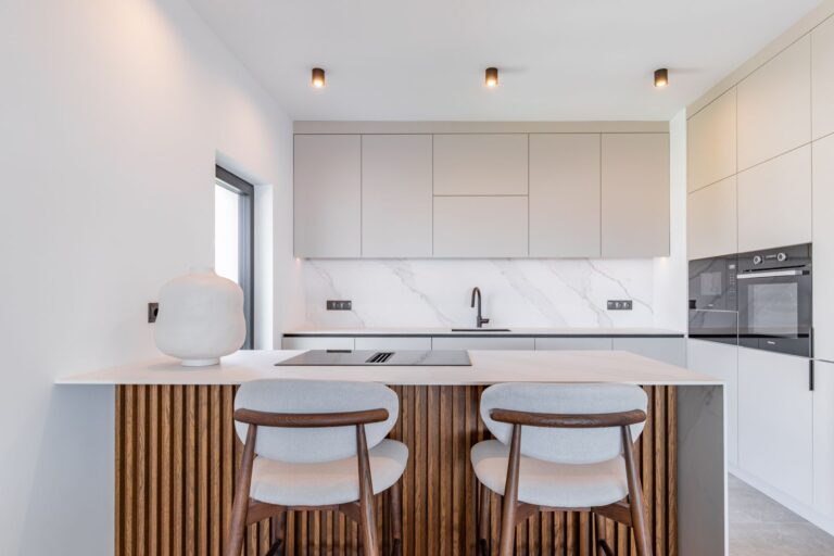 Kitchen island inside a luxury smart home villa near Moraira with integrated appliances, white cabinetry, bar seating and premium modern finish