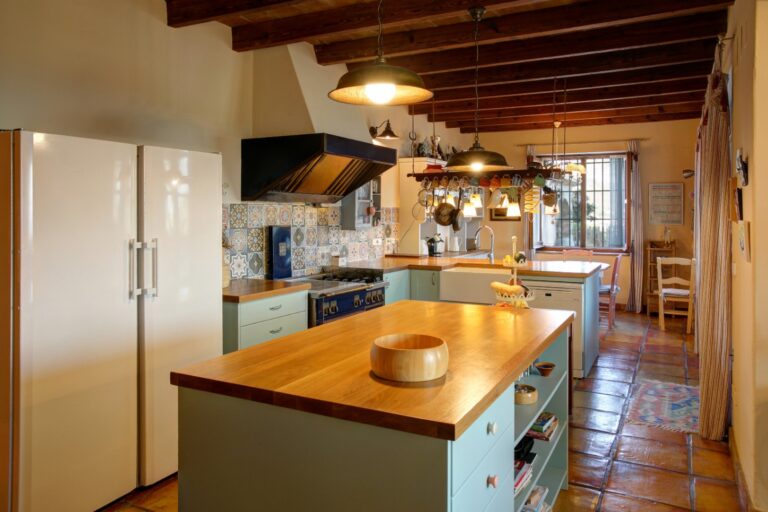 Kitchen island inside a rustic Mediterranean estate near Moraira with professional range, wooden worktops, exposed beams and warm traditional finishes