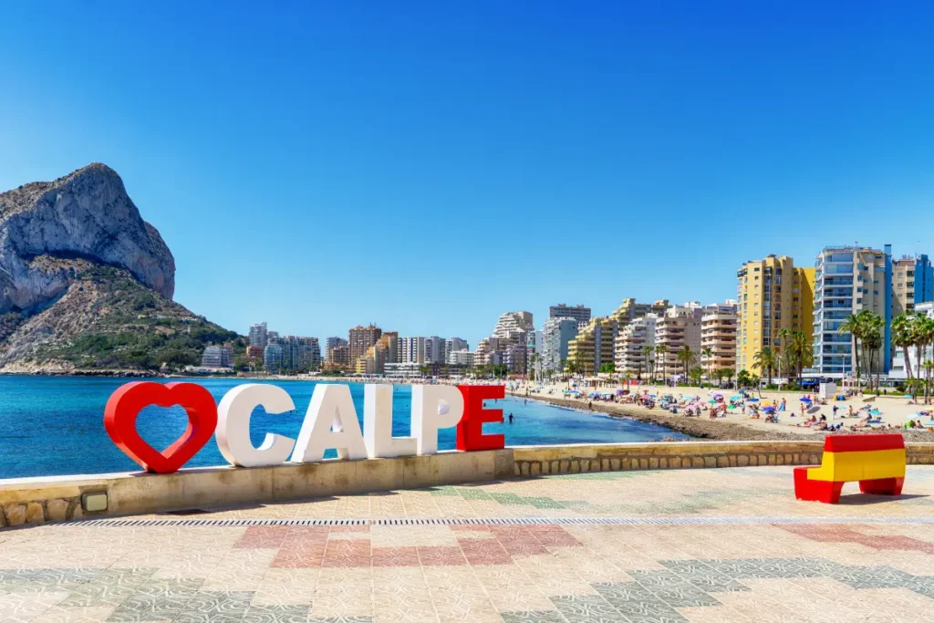 La Fossa Beach in Calpe with the Calpe sign, Peñón de Ifach and beachfront apartments in the background