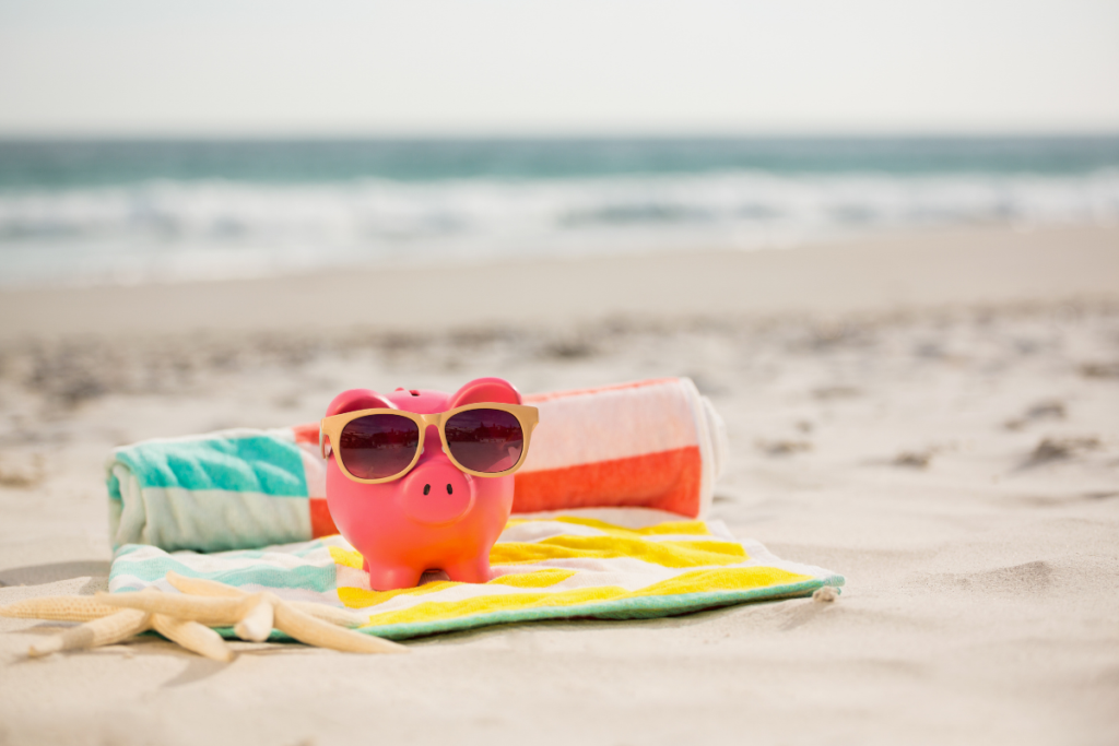 Piggy bank with sunglasses on a beach towel, representing holiday in La Fossa, Calpe