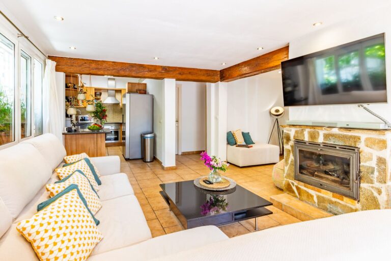 Living area inside a Mediterranean villa near Cala Baladrar in Benissa Costa with fireplace, open kitchen, exposed beams and bright interior