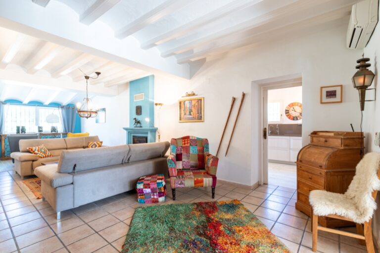 Living area inside a renovated finca near Teulada and Moraira with sofa seating, white beamed ceiling, tiled flooring and bright traditional interior