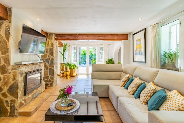 Living room inside a Mediterranean villa near Cala Baladrar in Benissa Costa with fireplace, stone details, sofa seating and garden access