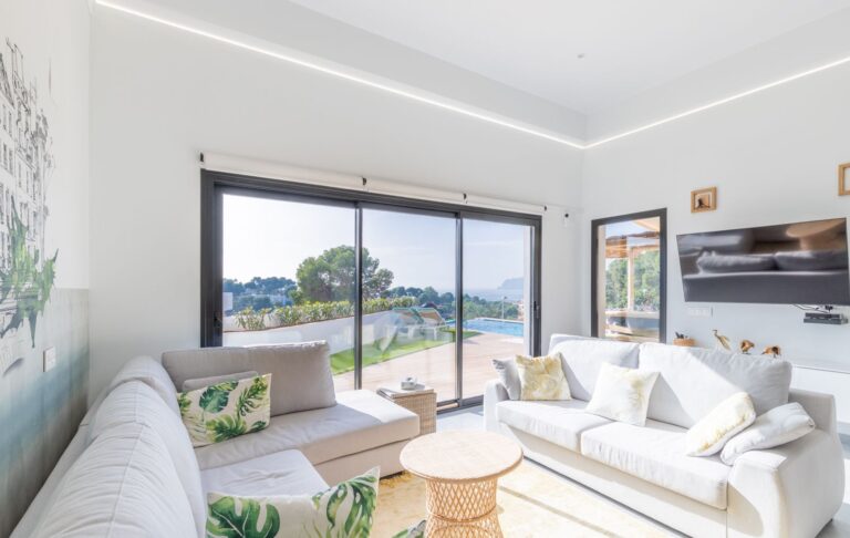 Living room inside a modern villa in Pla del Mar, Moraira with sofa seating, large windows, sea views and bright contemporary interior