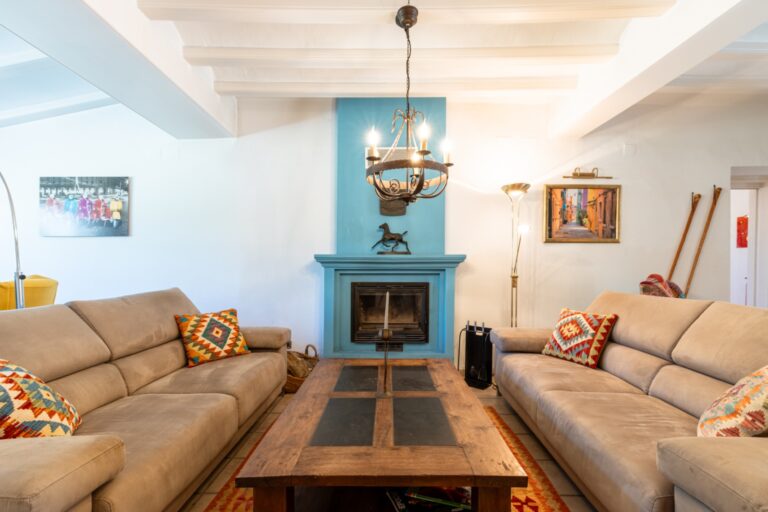 Living room inside a renovated finca near Teulada and Moraira with fireplace, sofa seating, white beamed ceiling and blue feature wall