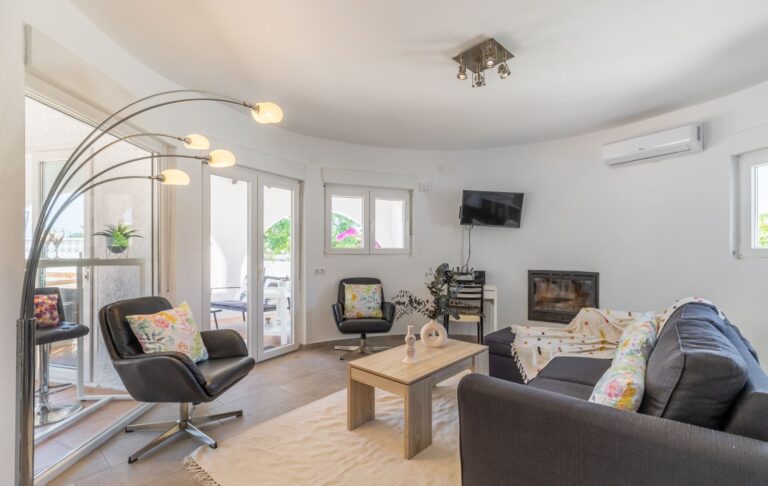 Living room inside a renovated Mediterranean villa near Cala Baladrar in Benissa Costa with fireplace, sofa seating, bright windows and modern finish