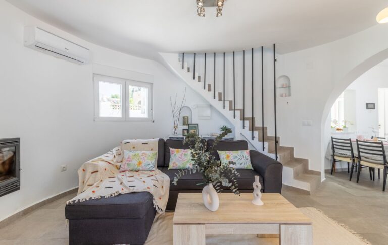 Living room inside a renovated Mediterranean villa near Cala Baladrar in Benissa Costa with sofa seating, staircase, fireplace and bright open layout