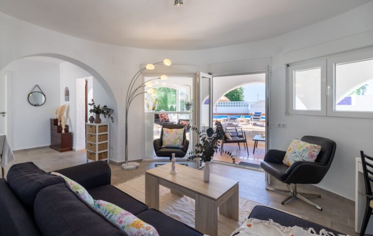 Living room inside a renovated Mediterranean villa near Cala Baladrar in Benissa Costa with terrace access, sofa seating, bright windows and pool area beyond