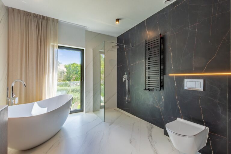 Luxury bathroom inside a smart home villa near Moraira with freestanding bath, large window, dark feature wall, walk-in shower and premium finishes