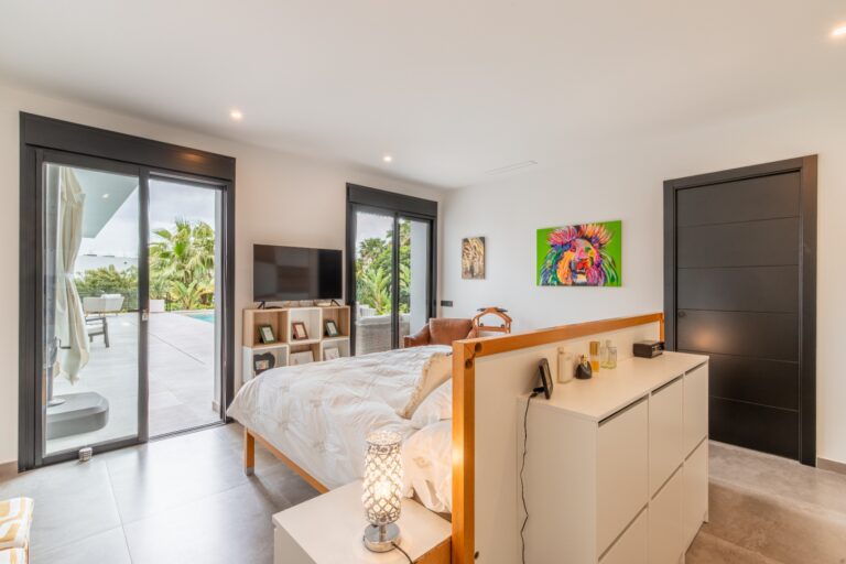 Master bedroom inside a modern villa in Solpark, Moraira with direct terrace access, double bed, seating area and modern neutral finishes