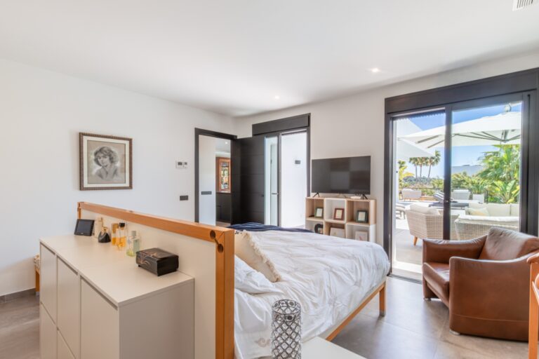 Master bedroom inside a modern villa in Solpark, Moraira with terrace access, fitted storage, seating area and bright contemporary interior