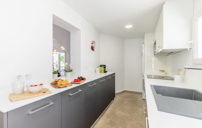 Modern kitchen inside a renovated Mediterranean villa near Cala Baladrar in Benissa Costa with grey cabinetry, white worktops and fitted appliances