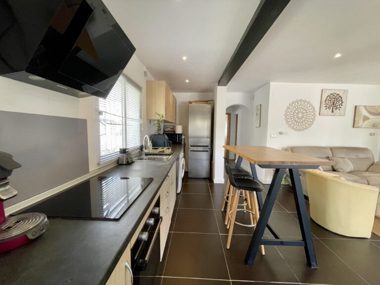Open-plan kitchen with breakfast bar connected to the living area in a Calpe villa