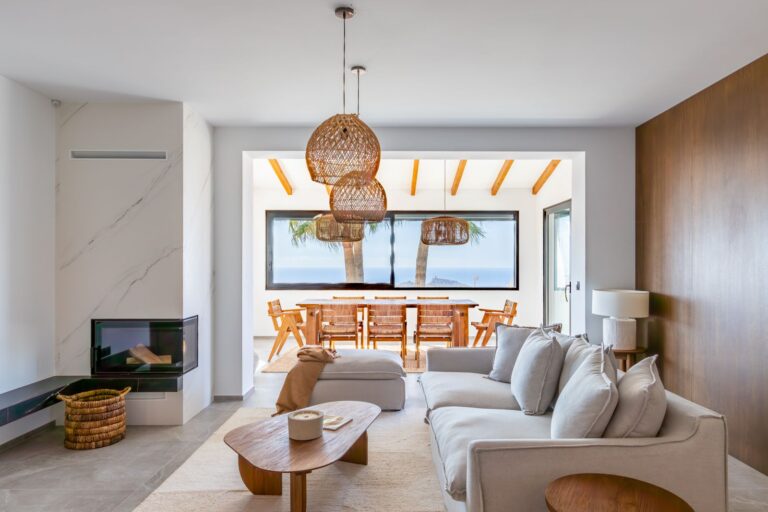 Open-plan living and dining area inside a luxury smart home villa near Moraira with fireplace, sofa seating, wooden dining area and bright modern interior