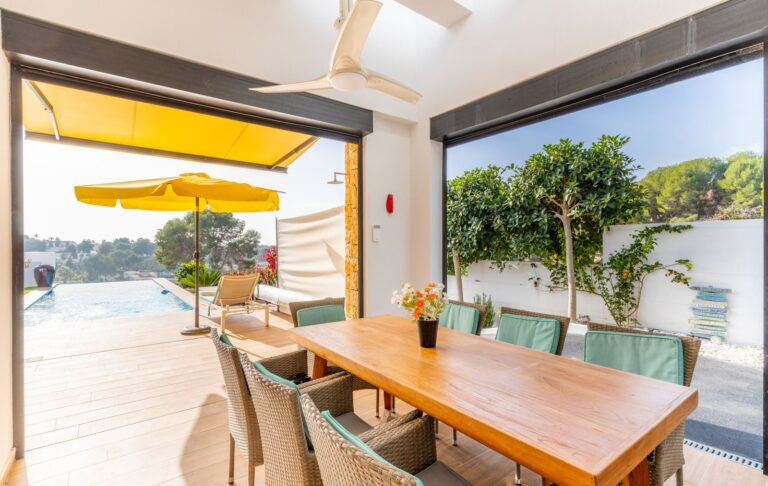 Outdoor dining area at a modern villa in Pla del Mar, Moraira with terrace access, yellow awning, sea views and bright contemporary design