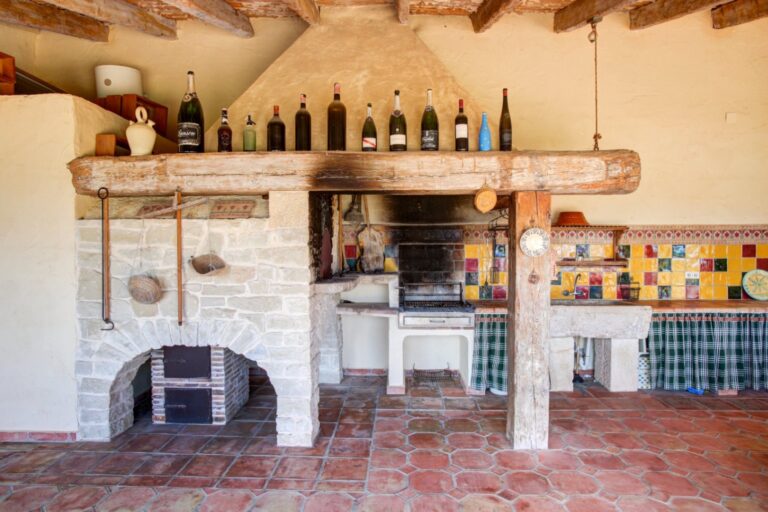 Outdoor kitchen at a rustic Mediterranean estate near Moraira with traditional barbecue, colourful tile detail, dining area and covered terrace