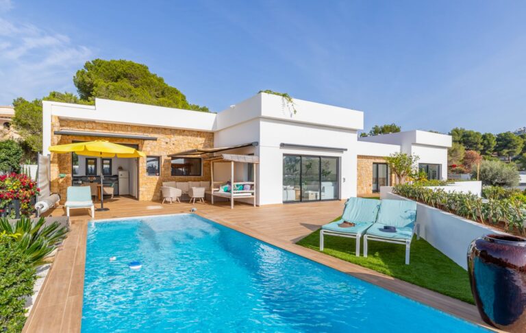 Pool terrace at a modern villa in Pla del Mar, Moraira with heated swimming pool, outdoor seating, yellow awning and contemporary white exterior