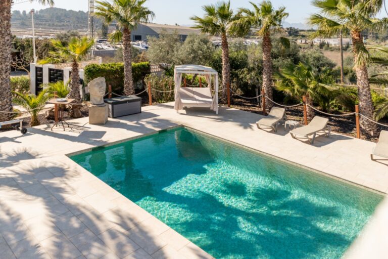 Pool terrace at a renovated finca near Teulada and Moraira with private swimming pool, sun loungers, palm trees and outdoor lounge area