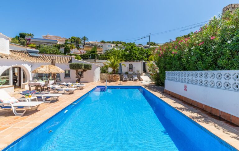 Pool terrace at a renovated Mediterranean villa near Cala Baladrar in Benissa Costa with private swimming pool, sun loungers and garden surroundings